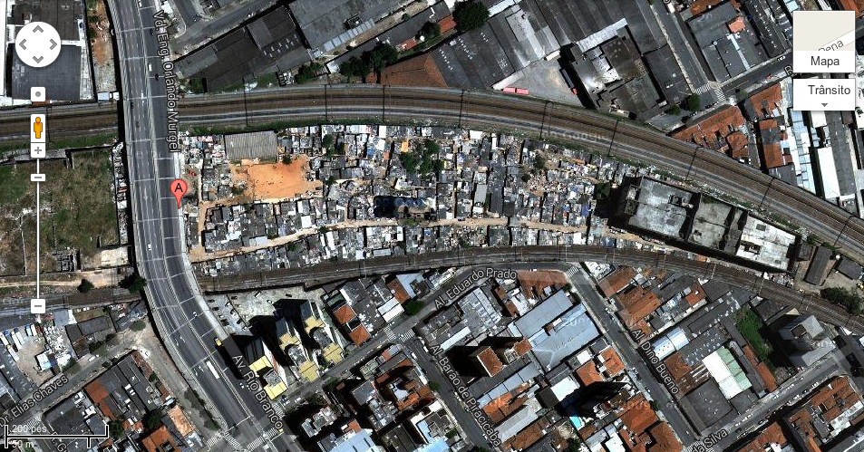 Favela do Moinho: erguida entre duas linhas de trem da CPTM. Na ponta à extrema direita da favela ainda se vê o edifício que foi demolido após o primeiro grande incêndio (2011). Foto/Google Maps